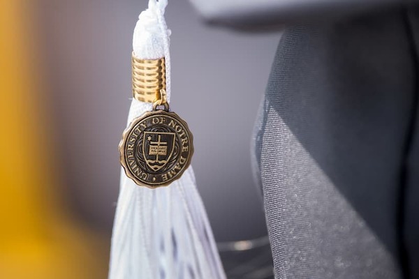 Close Up Photo Of A White Arts And Letters Tassel With The University Shield Medallion